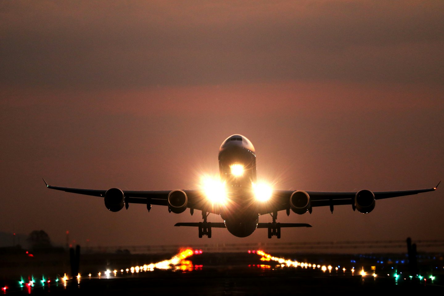 Aereo di linea che decolla da una pista al tramonto.